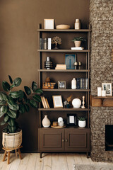 Shelving with books and decor near the brick fireplace and potted plants in a modern stylish living...