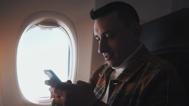 A man in a half-empty plane with a phone. Guy traveler looking at smartphone