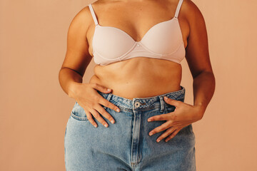 Unrecognizable curvy woman wearing a bra and jeans - Powered by Adobe