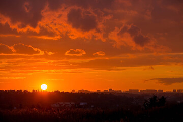 Banner. Beautiful red-orange fiery sunset over the city. Dark clouds in the sky. The outlines of...