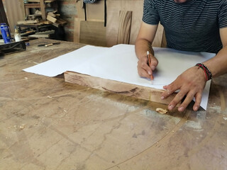 An Anonymous Carpenter Working on New Project at his Workshop. Table top view of unrecognizable man drawing n