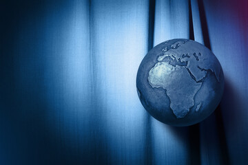 Metalic earth globe on blue fabric.