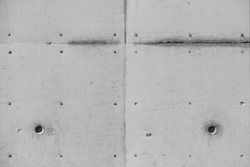 Concete wall of a building with wheathered facade. Traces like lines and dots from paving out the paneling. Architecture or construction site background with side light, black and white greyscale.