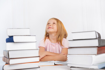 Portrait of a pensive little girl with a lot of big books. Back to school.
