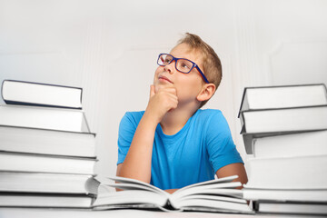 Portrait of a pensive, hardworking boy with a lot of big books. Back to school.
