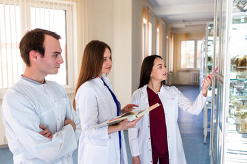 Group of medical students in uniform looking on the x-ray sitting at the desk in the modern classroom