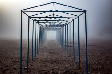 Seashore in winter in fog with metal structures and objects during the day