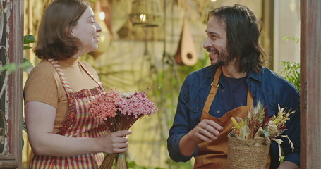 Male and female workers smiling and laughing at camera. Portrait of two happy employees wearing aprons inside local small business shop