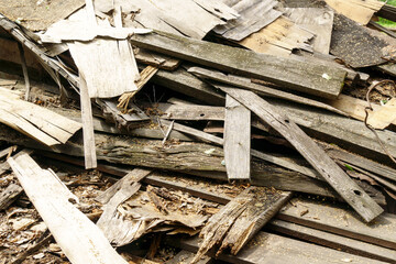 Piles of used wood and boards behind the house, various sizes with a wall background. Selective focus