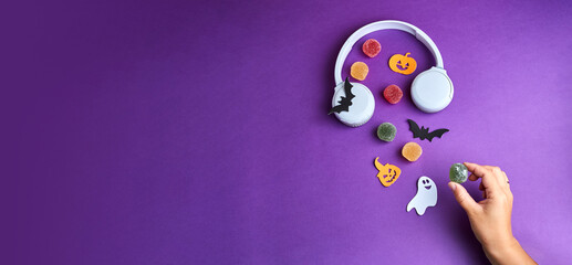 Halloween podcast. Halloween decorations, pumpkins, bats, candy, ghosts, on purple background. Halloween party greeting card. Copy space. Flat lay, top view, overhead.