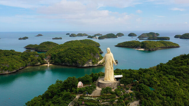 Aerial view of the hundred Islands national Park and the statue of Jesus Christ on top of the island, Pangasinan, Philippines. Cluster of Islands with beaches and lagoons, famous tourist attraction