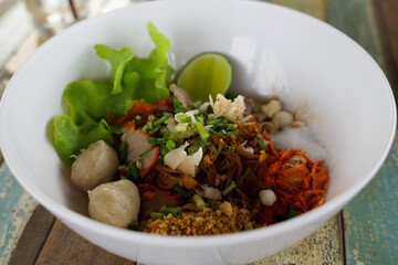 Closeup Spicy TOM YAM Pork Noodles Soup with Pork Balls, chilly pasted and lime juice  Noodles in Thai spicy tom yum soup with pork.