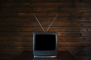 Old analoque retro tv with isolate black screen mock up on dark brown wooden background in room on...