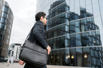 A businessman man goes to work in the office, in a business suit with a briefcase - obrazy, fototapety, plakaty