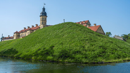 Moat of old castle. Moat with reflection in the water and trees. Sunny summer day. Palace, tower,...