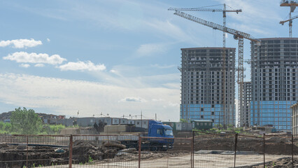 Fototapeta premium Construction of a multi-story residential buildings. A lot of construction equipment, cranes work. Construction site.