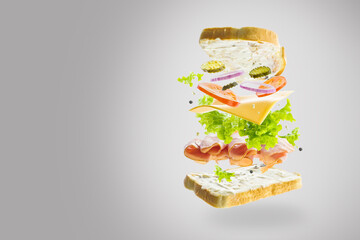 On a light gray background, an appetizing burger in a frozen flight. Fresh vegetables, greens, cheese, organic meat and two slices of white bread. There is free space to insert.