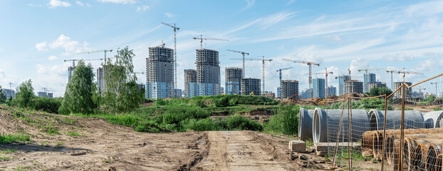 Construction of a multi-story residential buildings. Defocused foreground with young tree. Cranes...