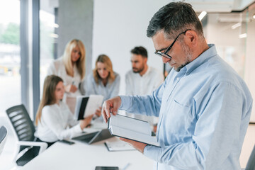 Obraz premium Portrait of senior man. Group of professional business people is in the office