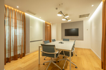 Boardroom of a professional office with tv on the wall and white swivel chairs