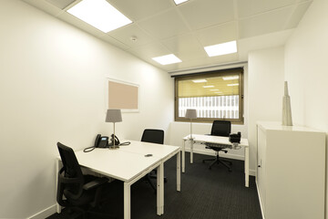 Cubicle in professional office with shared table, file, black swivel chairs