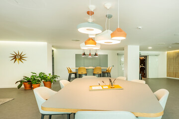 Professional coworking office with several meeting tables and lots of decorative ceiling lamps