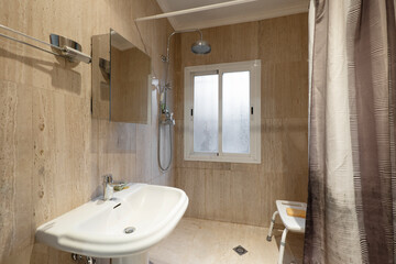 Bathroom with white porcelain sink, marble tiles and shower with seat
