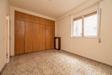 Empty bedroom stone floors, fitted wardrobes and chests completely covering the wall, radiator...
