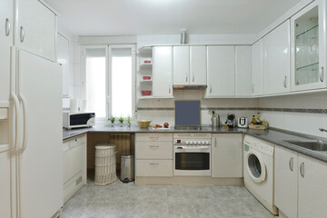 Kitchen with wooden furniture covering three walls with blue countertops, built-in white appliances...