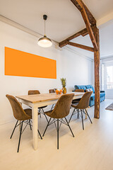 Studio living room with wooden dining table, brown velvet upholstered chairs and exposed wooden beams