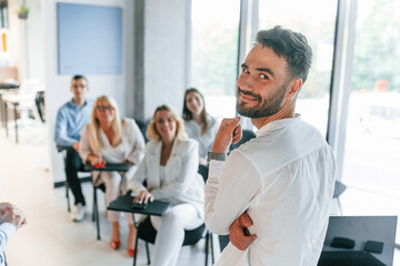 Man looking behind into the camera. Master class. Group of professional business people is in the office