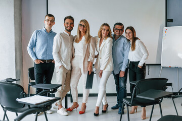 Standing and posing for a camera in the class. Group of professional business people is in the office