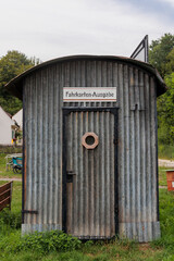 Old corrugated iron hut at the train station of St Ottilien in Bavaria with a window in the door and German text: Ticket issue