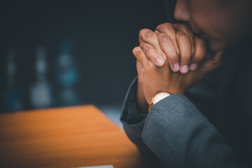 Pray and bible concept. Hand in hand together on bible by woman (worship christian), thinking and closed her eyes at church. Person side view, female praying, hope for peace.