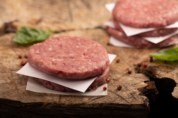 Obraz na płótnie Canvas Raw beef meat burger steak cutlets and dry red pepper wooden background