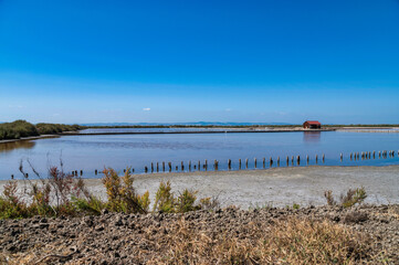 Tranquil view of the Samouco salt flats in Alcochete, Portugal, with a red hut and still water reflecting the sky