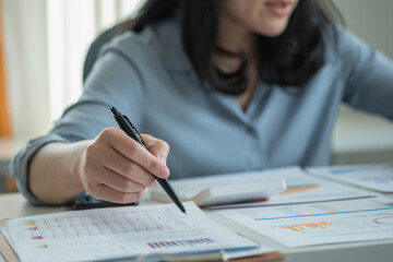 Business woman holding pen to present profit data in graph to supervisor via laptop computer.