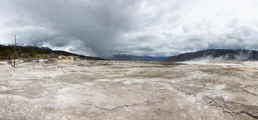 Hot spring Geyser with colorful water in American Landscape. Cloudy Sky. Yellowstone National Park, Wyoming, United States. Nature Background Panorama