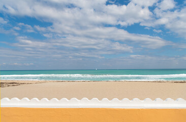 summer beach with yacht on horizon behind fence