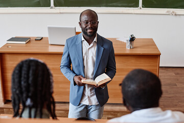 African professor reading lecture at university for students while standing in auditorium