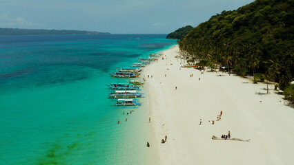 Sandy tropical beach with tourists and blue clear sea. Summer and travel vacation concept. Boracay, Philippines. Seascape with beach on tropical island. Puka shell beach