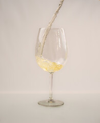 White wine glass, with wine falling on a white background