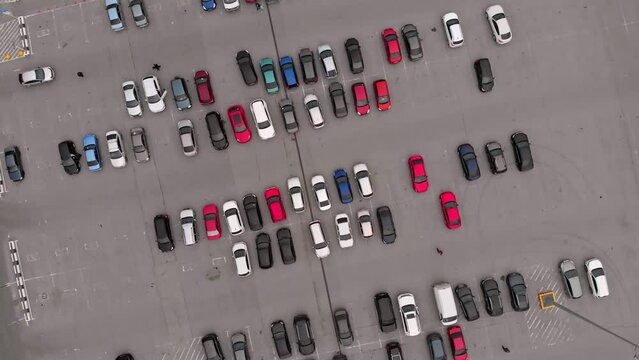 The drone rises above the cars parked in the large parking lot near the mall, customers can safely leave their car in the parking lot while shopping. A large number of cars in the parking lot.