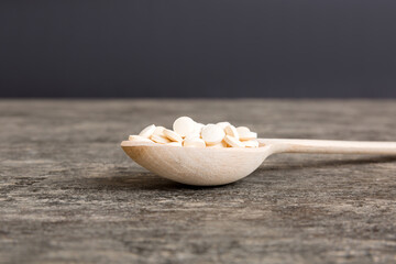 Heap of white pills on colored background. Tablets scattered on a table. Pile of red soft gelatin capsule. Vitamins and dietary supplements concept