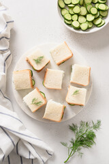 Cucumber sandwiches with ricotta and dill on white background. Top view. Copy space. Vertical format
