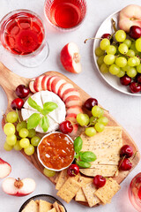 Healthy mediterranean cheese and fruits board with rose wine on light background