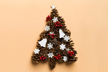 Christmas tree made from natural cones on colored background, view from above. New Year minimal concept with copy space
