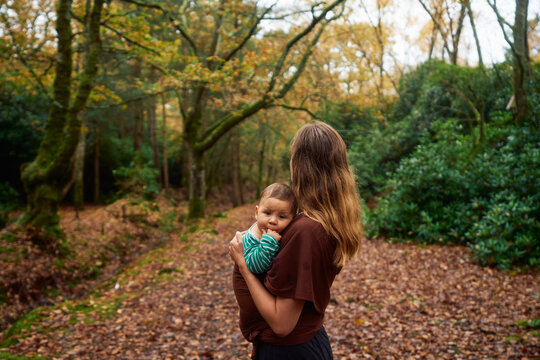 Young mother standing in the woods with her baby