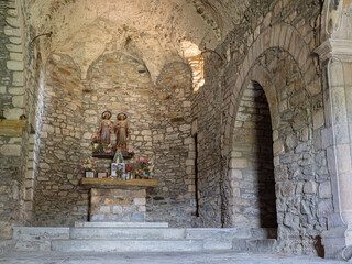 Interior de la Iglesia de Sant Cebrià de Lledó, en Girona, viendo arcos de piedra y figuras de santos en un altar, en España, otoño de 2021