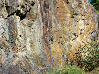 Vistas del corte de una montaña, con colores de otoño, ocre, rojizo, amarillo, beige de textura rugosa.